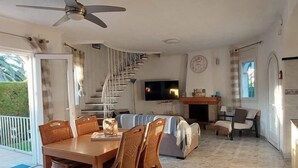 Ein großzügiger Wohnbereich mit Esstisch, Stühlen, einer Couch, einem Fernseher und einer Treppe.