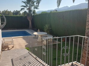 A backyard with a swimming pool, a round table, and a white fence. - Charming detached house with private pool in Miami Playa (Mont-roig del Camp)
