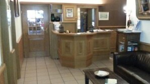 Un salon avec un canapé en cuir marron, une table basse et un coin cuisine doté de meubles en bois et d’un plan de travail.