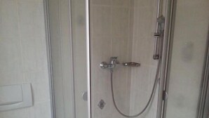 Une salle de bain avec une douche à parois de verre, des toilettes et un lavabo.
