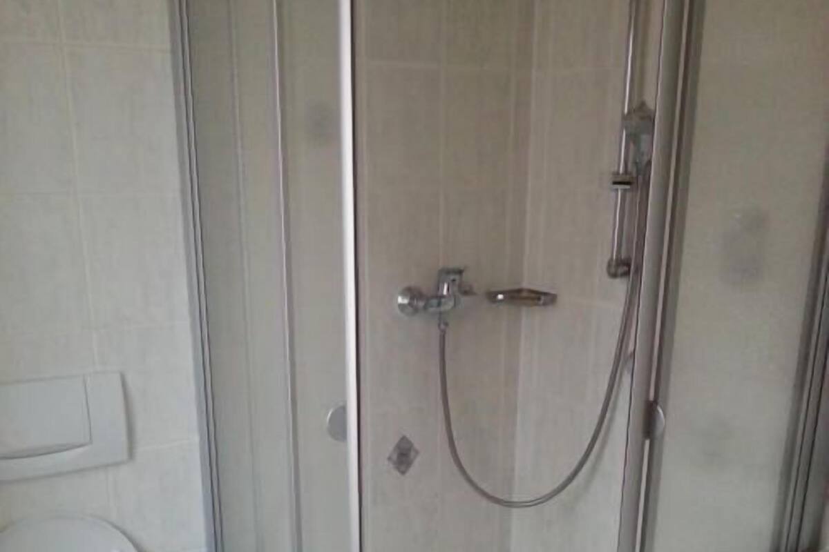 Un baño con ducha de vidrio, inodoro y lavamanos.