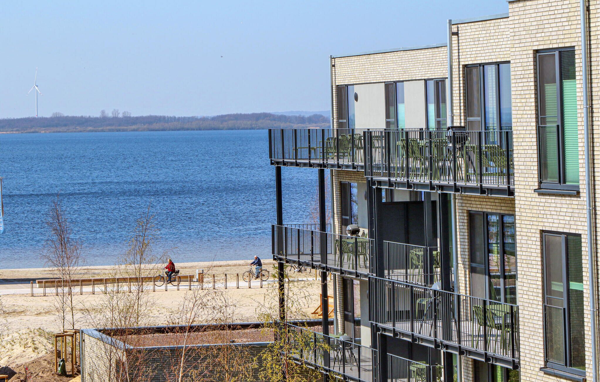 Un bâtiment moderne doté de nombreux balcons qui donnent sur une étendue d’eau.