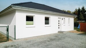 Un bâtiment d’un seul étage, à l’extérieur blanc, avec un toit recouvert de tuiles sombres et une allée gravillonnée.