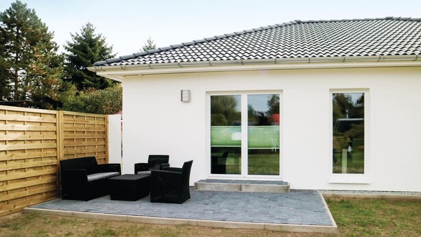 Une maison moderne dotée d’un patio aménagé avec du mobilier d’extérieur.