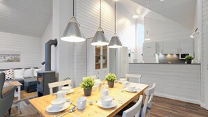 Una cucina moderna con mobili bianchi e una zona pranzo con tavolo in legno apparecchiata per quattro persone.