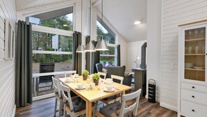 Zona pranzo con tavolo di legno, sedie e una credenza con vetrate.