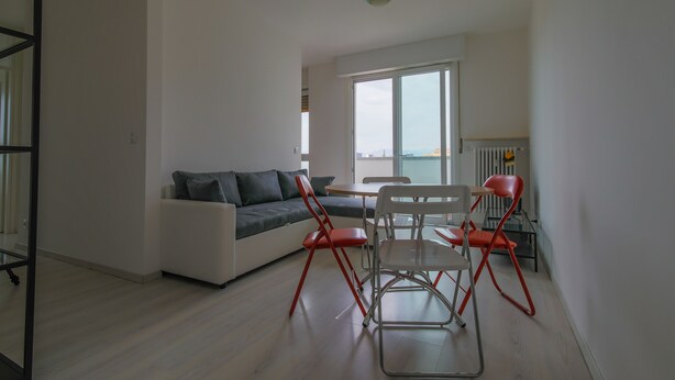 Una sala de estar moderna con un sofá, una mesa de comedor y sillas rojas.