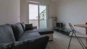 Una sala de estar moderna con un sofá gris, una mesa de vidrio y un televisor.