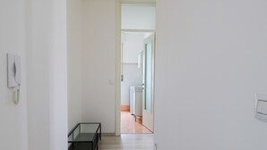 Un pasillo estrecho con un banco, un teléfono y una puerta que da a un baño.