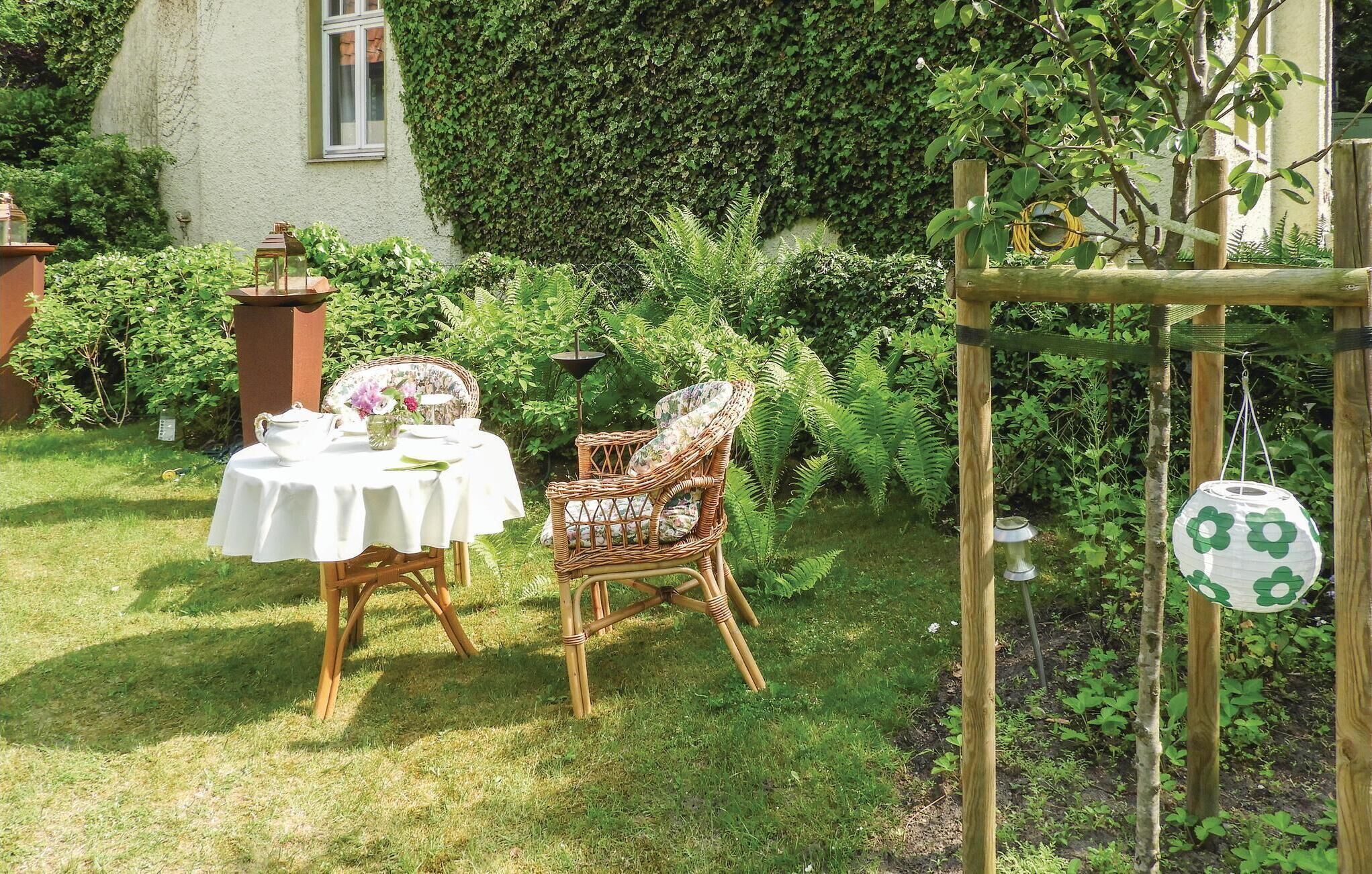 Un jardin extérieur avec une table et des chaises, une pergola en bois et un mur recouvert de lierre.