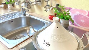 A kitchen with a stainless steel sink, a white teff container, and various kitchen utensils.
