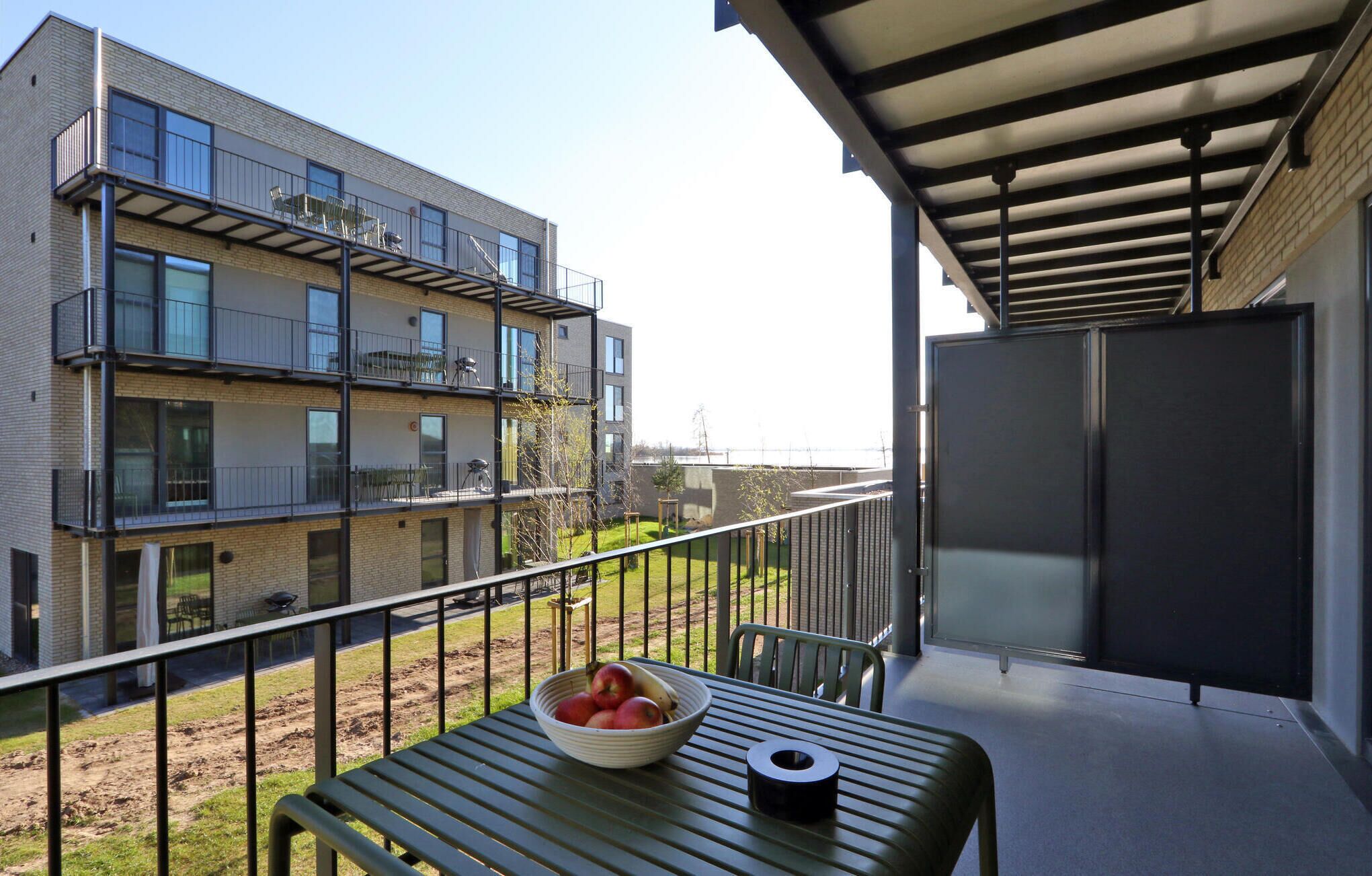 A balcony with a table, a bowl of fruit, and a chair.