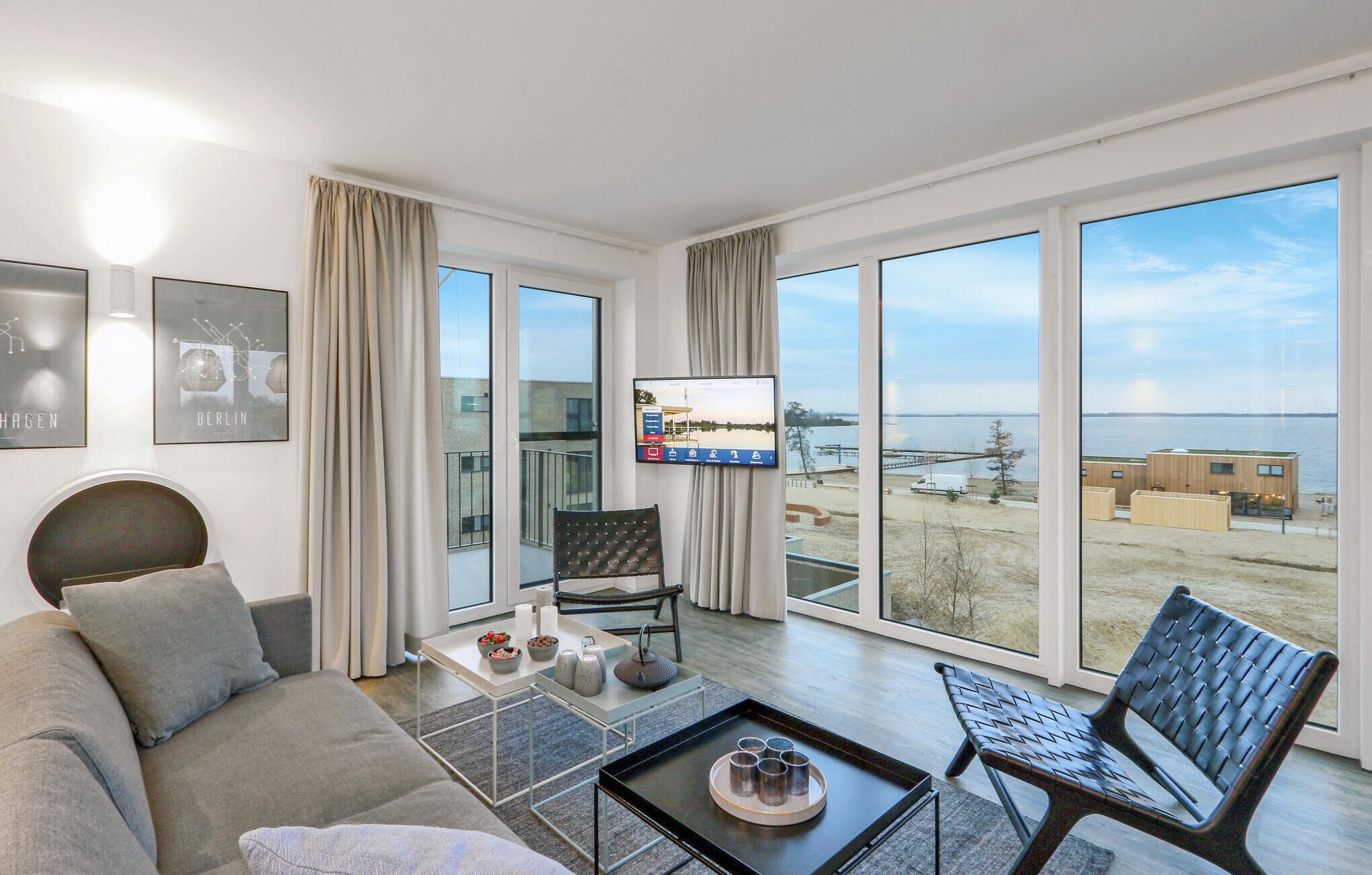 A modern living room with a large window, a flat-screen TV, a sofa, a coffee table, and a chair.