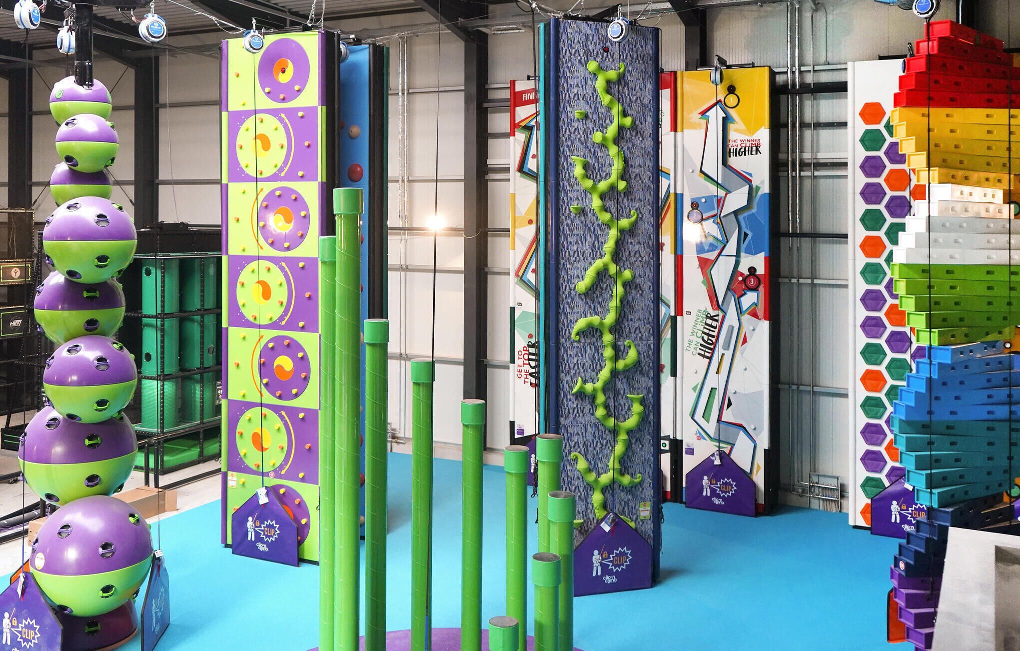 A colorful indoor play area with various climbing structures and a large LEGO wall.