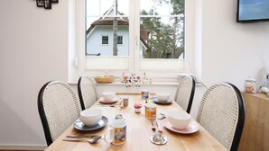 En matplats med ett träbord dukat för fyra personer, omgiven av stolar i rotting.