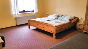 Une chambre à coucher avec un lit en bois, un radiateur, une fenêtre avec des rideaux et une table de chevet avec une lampe.