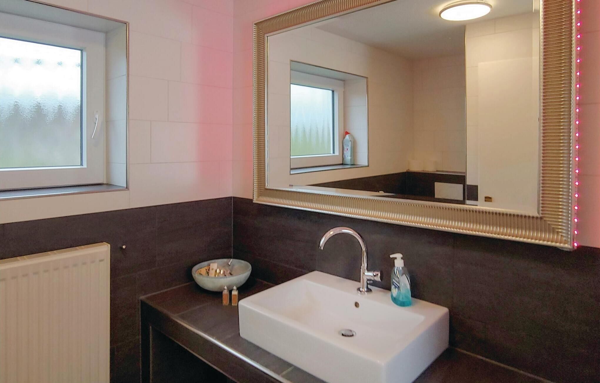 A bathroom with a white sink, a mirror, and a window.