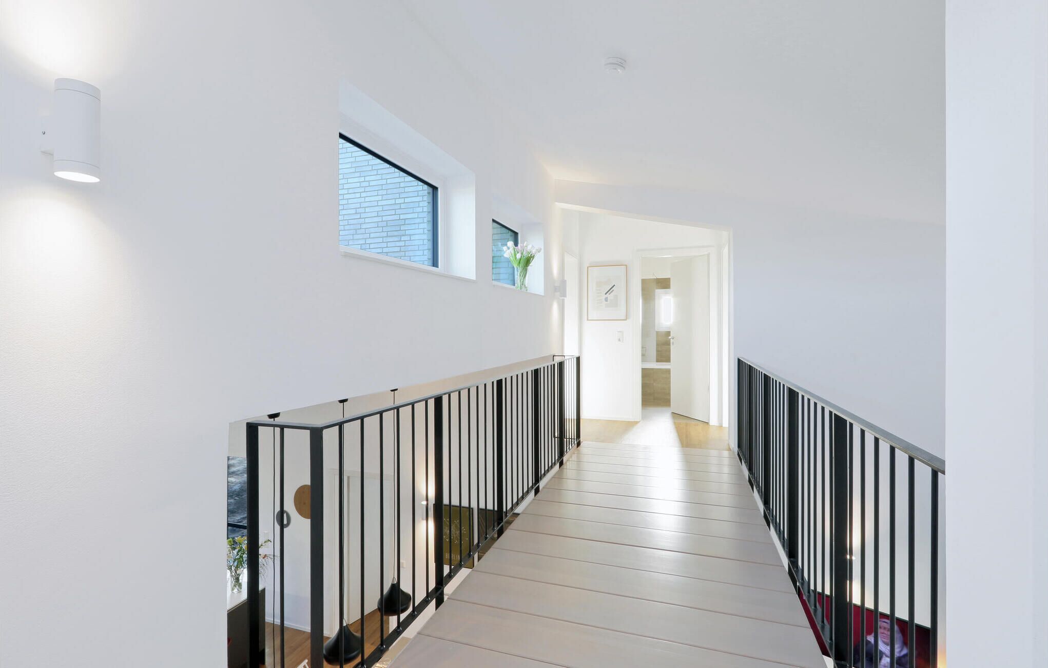 Eine moderne Treppe mit weißer Innenausstattung, schwarzen Geländern und Blick in den angrenzenden Raum.