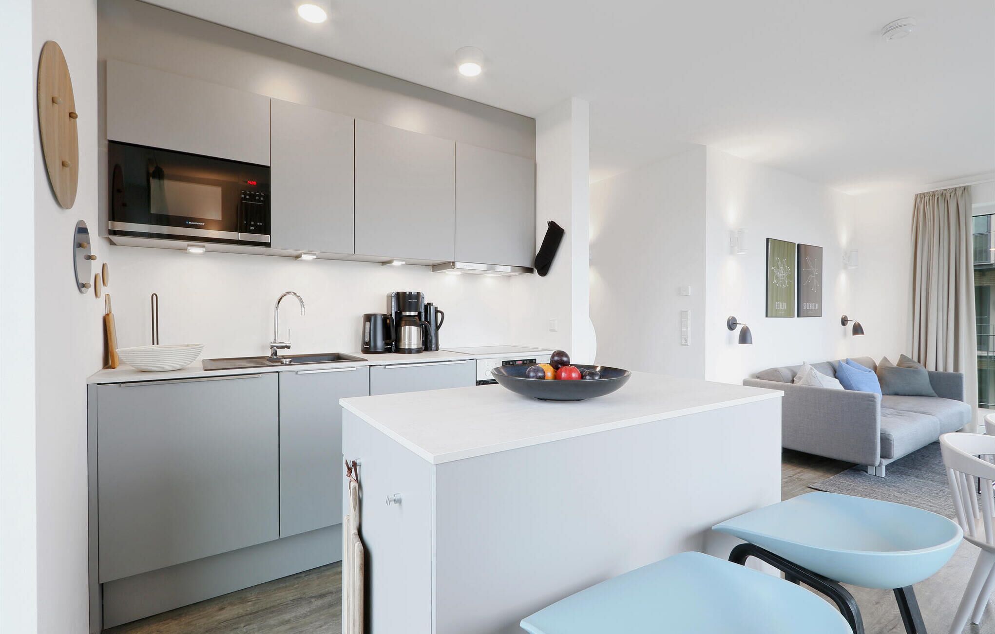 A modern kitchen with a central island, a built-in oven, and a coffee maker.