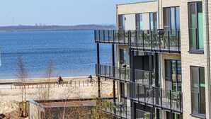A modern building with multiple balconies overlooking a body of water. - Beach front apartment in Lembruch/Dümmer See with lake view (Lembruch/Dümmer See)