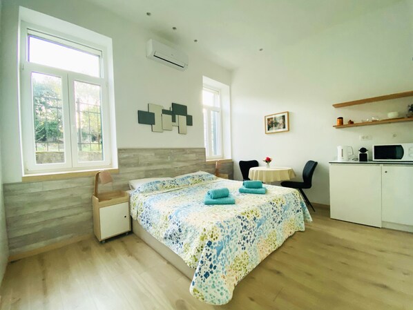 Une chambre comprenant un lit, un bureau, une chaise et un coin cuisine.