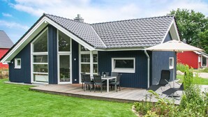 Ein modernes Haus mit einer großen Terrasse, einem Essbereich und einem Garten.