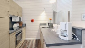 Eine moderne Küche mit Holzschränken, einer Mikrowelle, einer Kaffeemaschine und einem Spülbecken.
