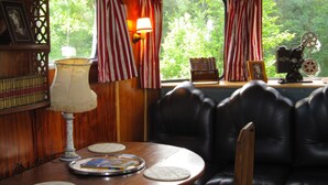 A cozy cabin interior with a leather couch, a table with a lamp, and a window with curtains. - Vacation home, great views, billiards, large spaces (Manses)