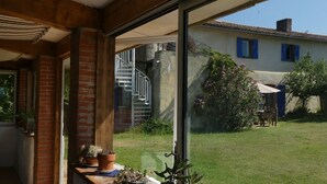 A room with a large window, a brick wall, and a staircase leading to an upper level. - Vacation home, great views, billiards, large spaces (Manses)