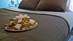 Una cama bien hecha con una colcha marrón, un plato de comida sobre la cama y un reloj en la mesita de noche.