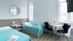 A hotel room with two beds, a desk, a chair, a small table with a vase, and a large mirror on the wall. - En-suite Iris on Rokova Street (Split)