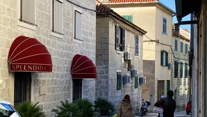 A narrow street with stone buildings, a red awning with 'Splendida' written on it, and potted plants along the sidewalk. - En-suite Iris on Rokova Street (Split)