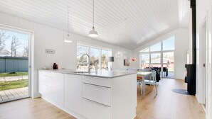 A modern kitchen with a large island, white cabinetry, and pendant lighting. - Nice home in Glesborg with sauna (Glesborg)