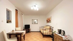 A small, well-lit room with a bed, a TV, a table with chairs, and a cabinet. - Apt Lavender on Nincevica St-1 BR Apt (Split)