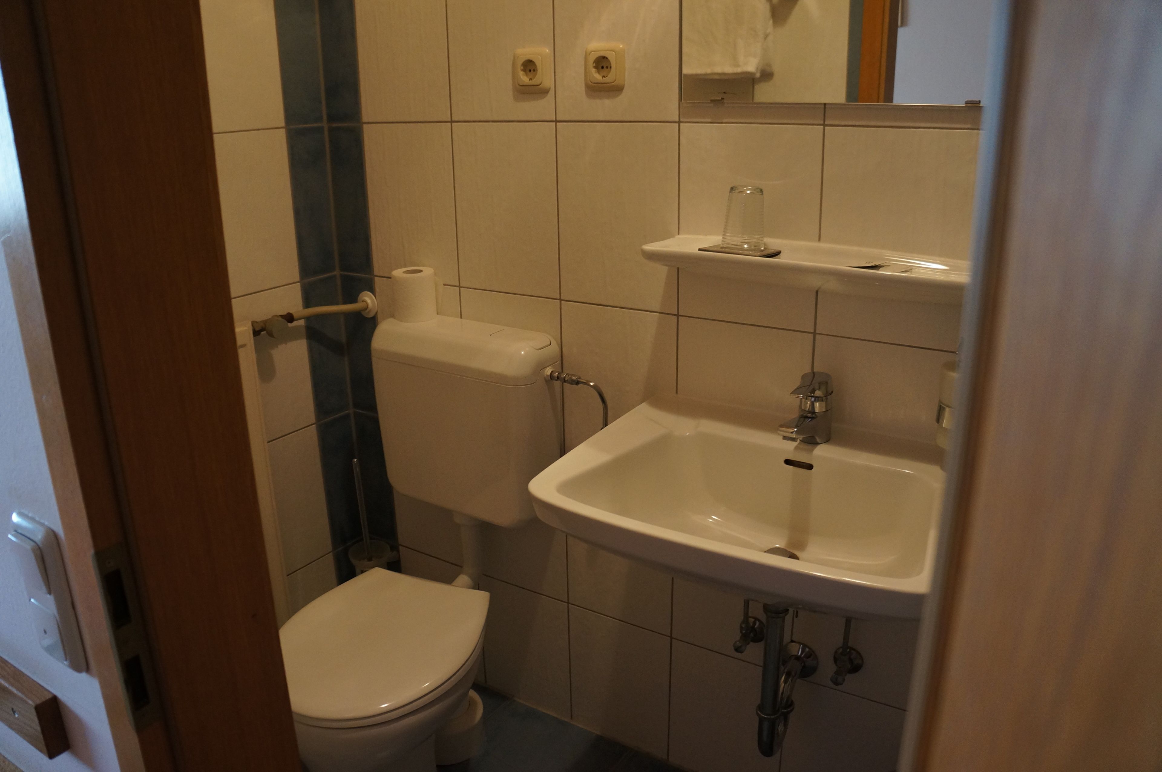 A bathroom with a toilet, sink, and mirror.