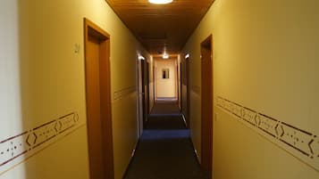 A hallway with wooden doors, numbered 20, and a carpeted floor.