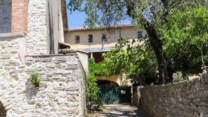 A narrow stone pathway leading to a building with a rustic facade, surrounded by trees and a clear blue sky. - MAS ABICOU - chambres d'hôtes (Vezenobres)