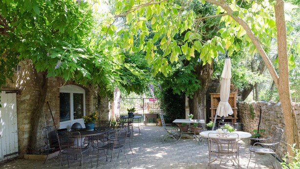 An outdoor patio area with brick flooring, metal chairs, and tables. There are potted plants and a wooden bench. - MAS ABICOU - chambres d'hôtes (Vezenobres)