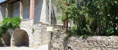 A stone building with arched doorways and a signpost.