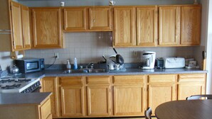 A kitchen with wooden cabinets, a microwave, a coffee maker, and a toaster.