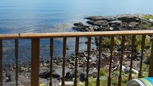 A wooden deck overlooking a calm lake with rocky shores and a distant forested island.