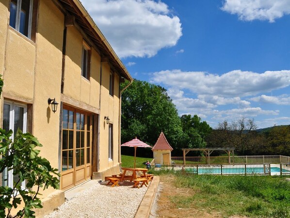 A building with large windows, a pool, and outdoor seating.