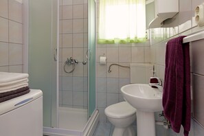 A bathroom with a shower, toilet, sink, and stacked towels. - House Ivan (Vela Luka)