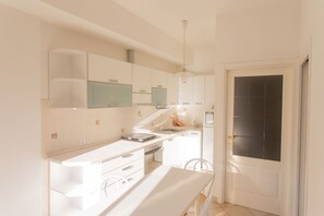 A modern kitchen with white cabinetry, a built-in oven, and a dining area with a white table and chairs. - N044 - Numana, new three-room apartment with terrace and a / c (Numana)