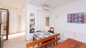 A room with a wooden table, a bench, a dining table with chairs, a white sofa, and a wall with marathon posters. - N044 - Numana, new three-room apartment with terrace and a / c (Numana)