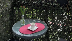 Un balcon avec une table, un vase avec une fleur et une vue sur un bâtiment historique.