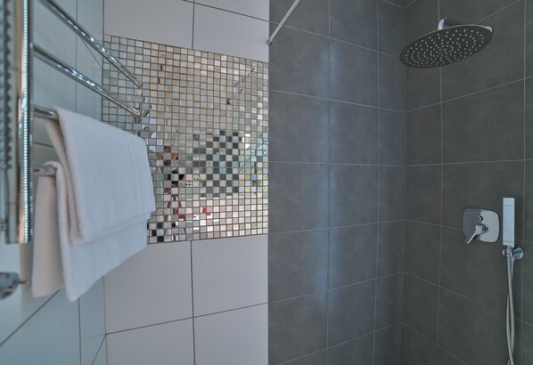 A modern bathroom with a shower, a tiled wall, and a towel rack.