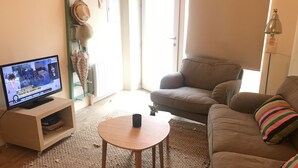 Una sala de estar con televisor, sofá, mesa de centro y alfombra estampada.