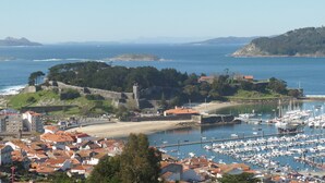Un pueblo costero con una fortaleza histórica, un puerto deportivo con numerosos barcos y una combinación de edificios residenciales y comerciales.