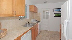 A compact kitchen with wooden cabinets, a white stove, and a sink. - The South Beach Party House (Miami Beach)